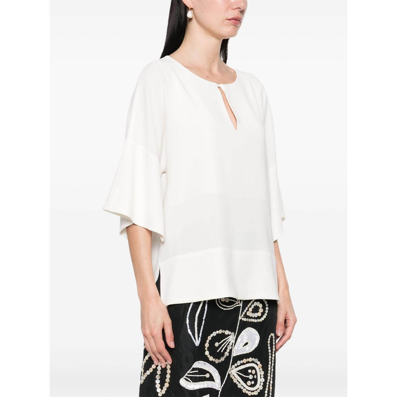 Model wearing Alberto Biani white blouse with teardrop opening, drop shoulder, three-quarter sleeves, and short side slits.