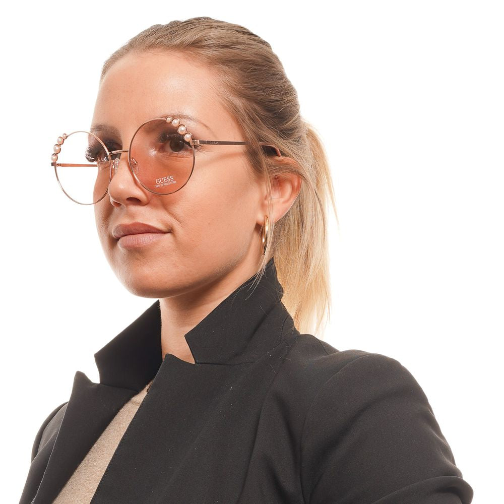 Woman wearing Guess Rose Gold round sunglasses with rose lenses, metal frame, offering 100% UVA & UVB protection.