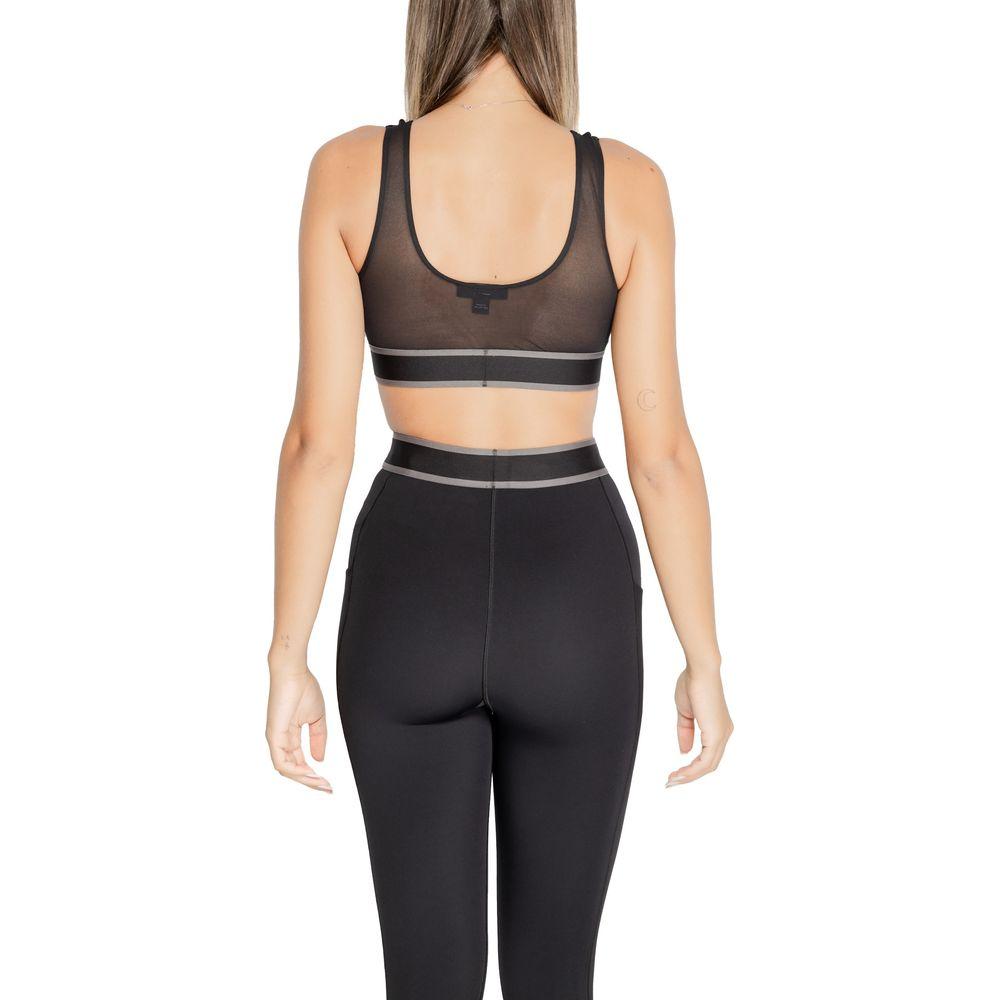 Back view of a woman wearing a Calvin Klein Sport black polyester sports bra and leggings, showcasing comfortable and seamless fit.