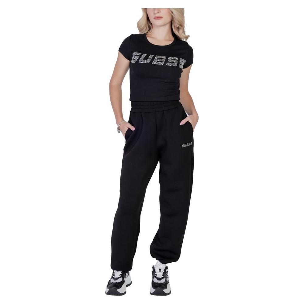 Woman wearing Guess Active black cotton t-shirt and pants, embossed logo visible, showcasing sporty style and comfort.