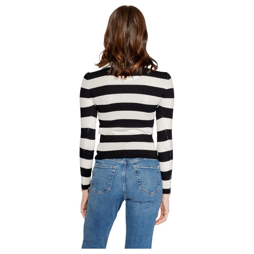 Back view of woman wearing black and white striped knit top with fitted jeans.