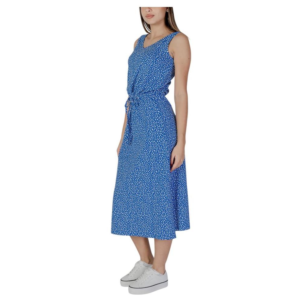 Woman wearing a blue sleeveless maxi dress with white sneakers, side view