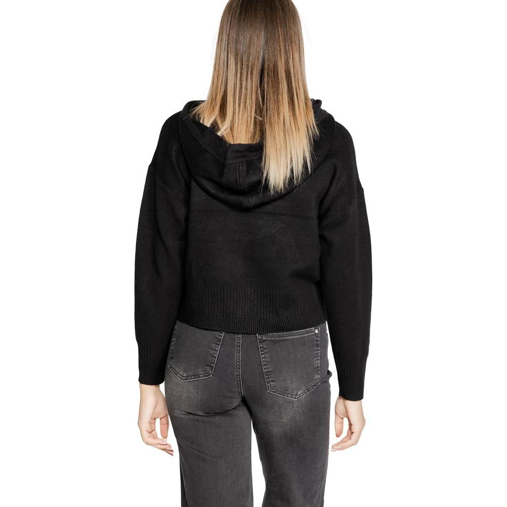 Woman wearing Vero Moda black viscose knit top, fall/winter collection, back view showing hoodie style.