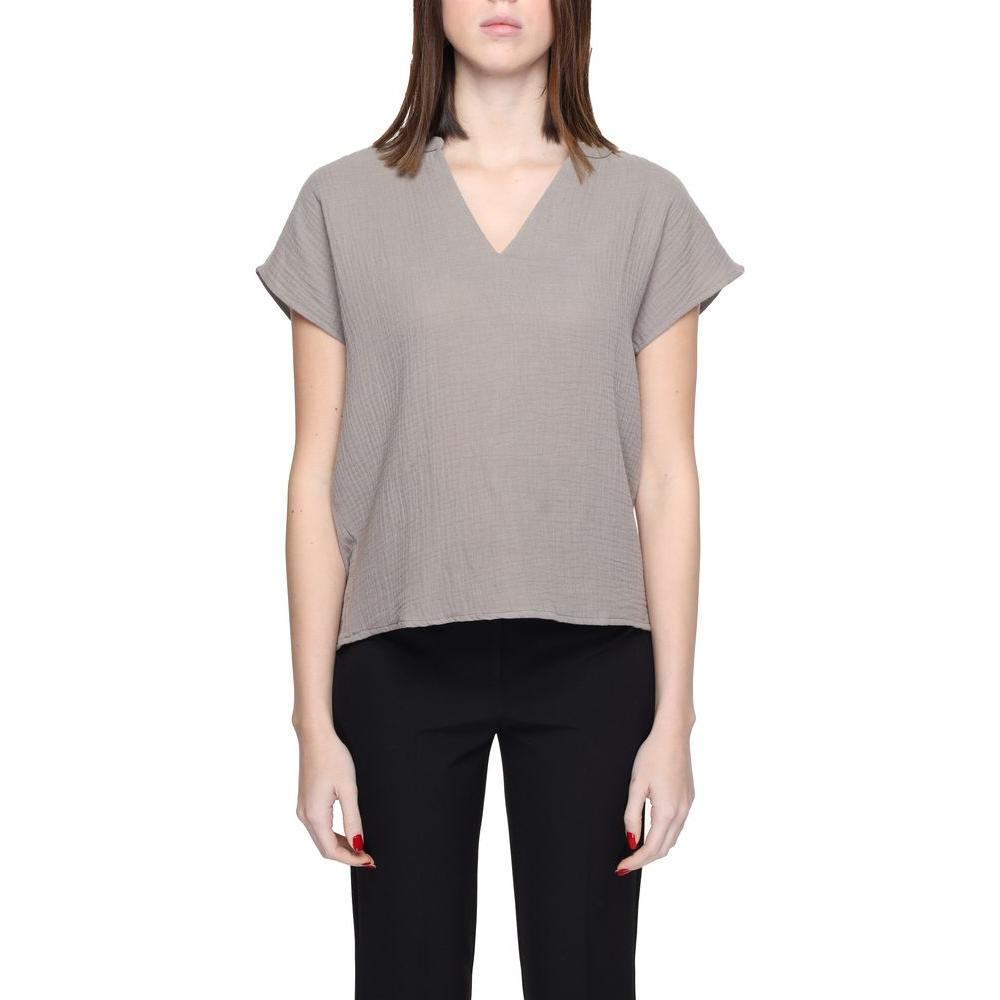 Woman wearing Jacqueline De Yong gray cotton short sleeve blouse, 80% cotton, 20% recycled cotton, eco-friendly fashion.
