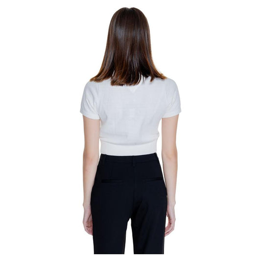 Back view of a woman wearing a white Tommy Hilfiger short sleeve top, yarn knit, from the Fall/Winter collection, paired with black pants.