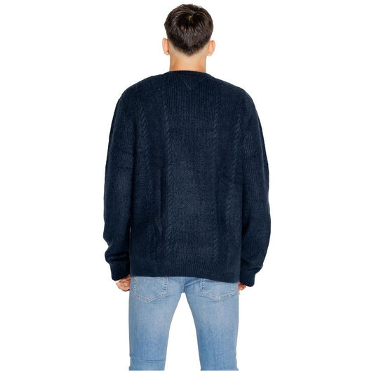 Back view of a man wearing a Tommy Hilfiger blue acrylic sweater with jeans, part of men's knitwear for fall/winter collection.