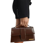 Jacquemus Brown Leather Handbag being held by a person in black outfit