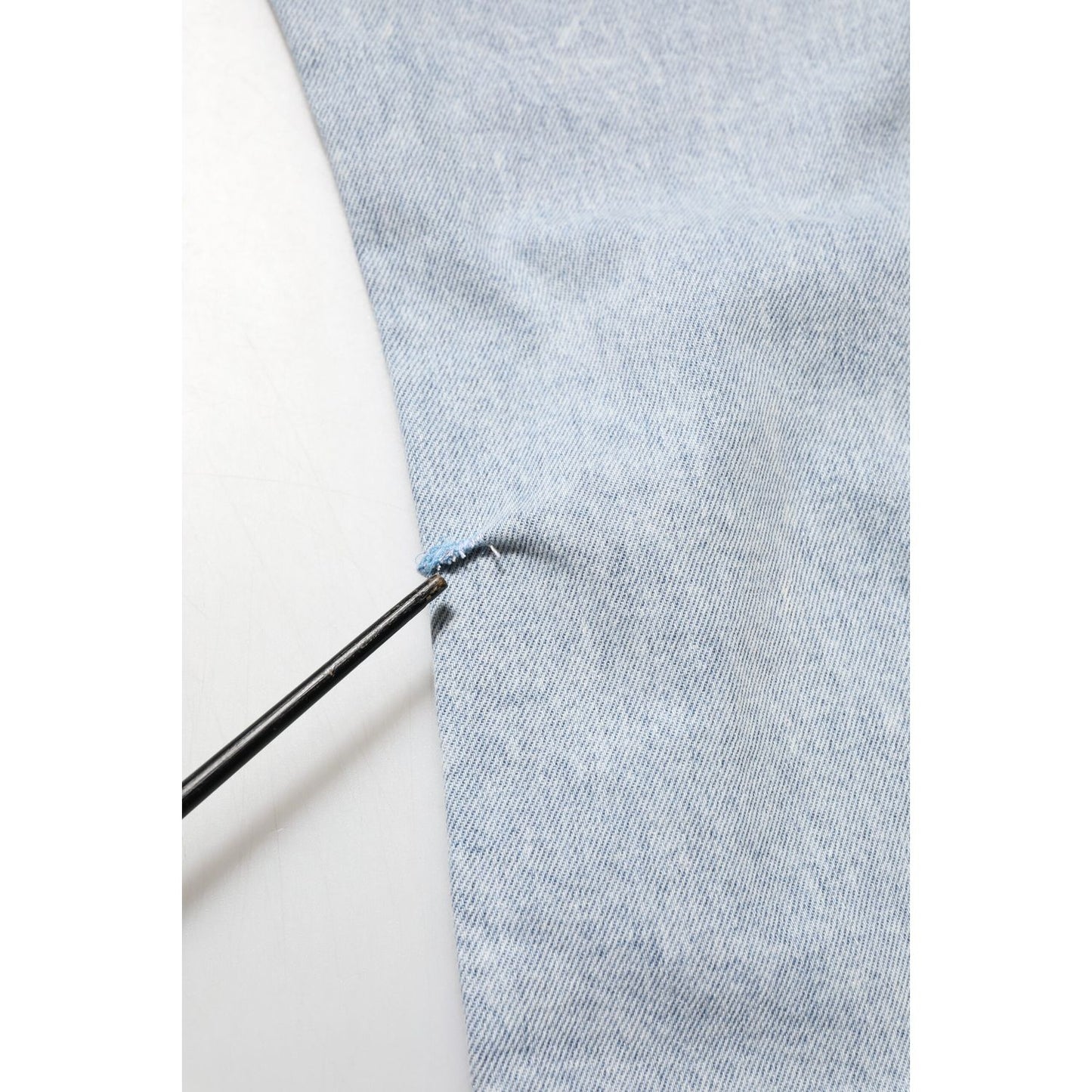 Detail of Dolce & Gabbana Light Blue Distressed Slim Fit Ripped Denim Jeans fabric showing distressed area with close-up view.