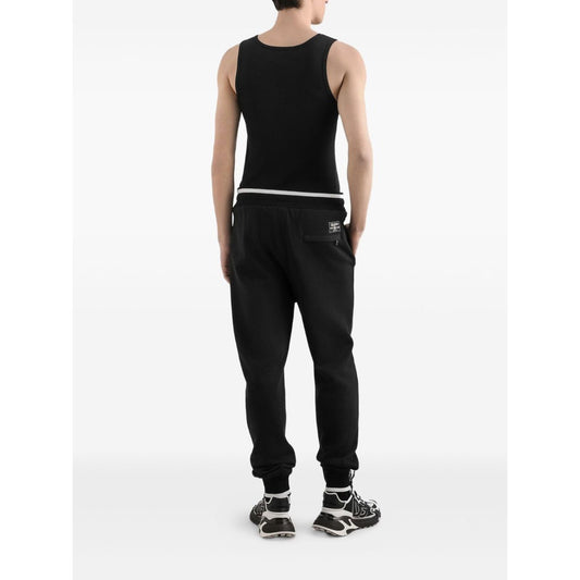 Back view of model wearing Dolce & Gabbana Logo cotton tank top with black embroidered logo, round neck, sleeveless, straight hem.