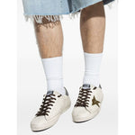 Golden Goose Super-Star in nappa leather with leather star and leather heel tab, white sneakers with lace-up and star detail, worn with denim.