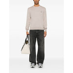 Man wearing Maison Kitsuné Maison Kitsune Fox motif sweater in light beige, with black jeans and sneakers, carrying a white bag.