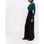 Norma Kamali Trousers Black high-waisted flared style with slit pockets, modeled with turquoise top, showcasing elegant design