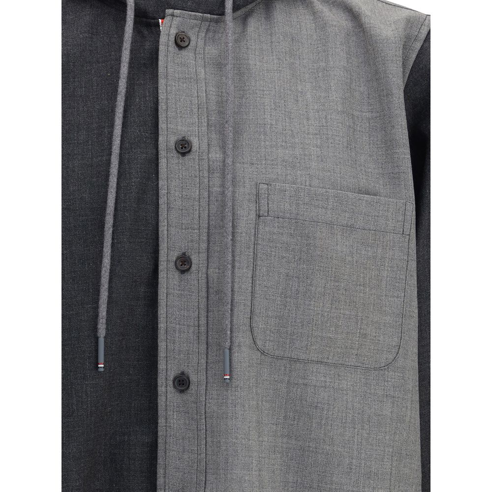 Close-up of Thom Browne Hooded Shirt Jacket with drawstring hood, button closure, chest patch pocket, and iconic signature patch, AW25 season.
