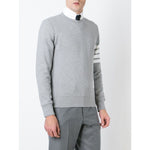 Model wearing Thom Browne Sweaters Grey featuring 4-Bar stripe, V insert crew neck, ribbed trims, and button side fastening.