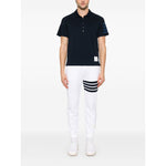 Model wearing Thom Browne Trousers White with elasticated drawstring waistband, side pockets, logo patch, and grosgrain loop tab.
