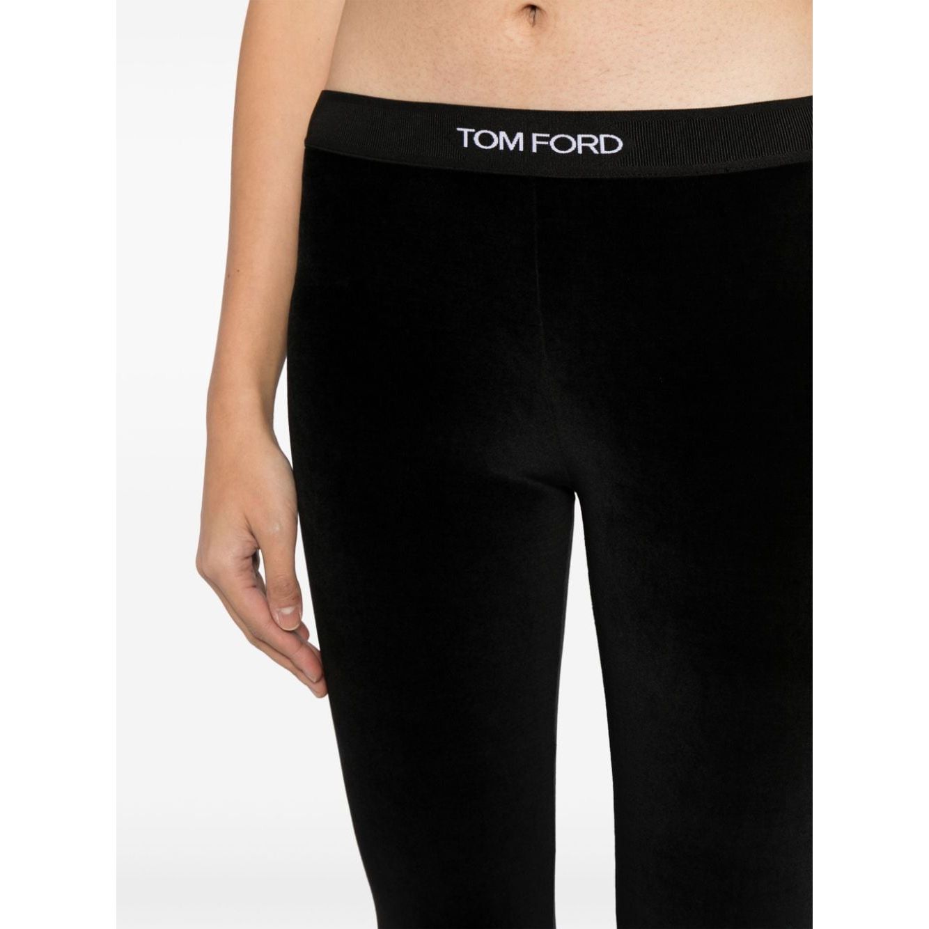 Model wearing Tom Ford Trousers Black velvet leggings with elasticated logo waistband, showcasing stretch design in close-up.