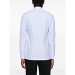 Back view of a Valentino Striped shirt in light blue with buttoned cuffs and embroidered motif, worn by a model.