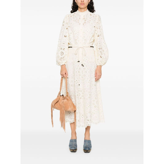 Woman wearing Zimmermann Shirts Ivory, embroidered blouse, with long sleeves, cut-out floral details and elastic cuffs, holding a tan bag.
